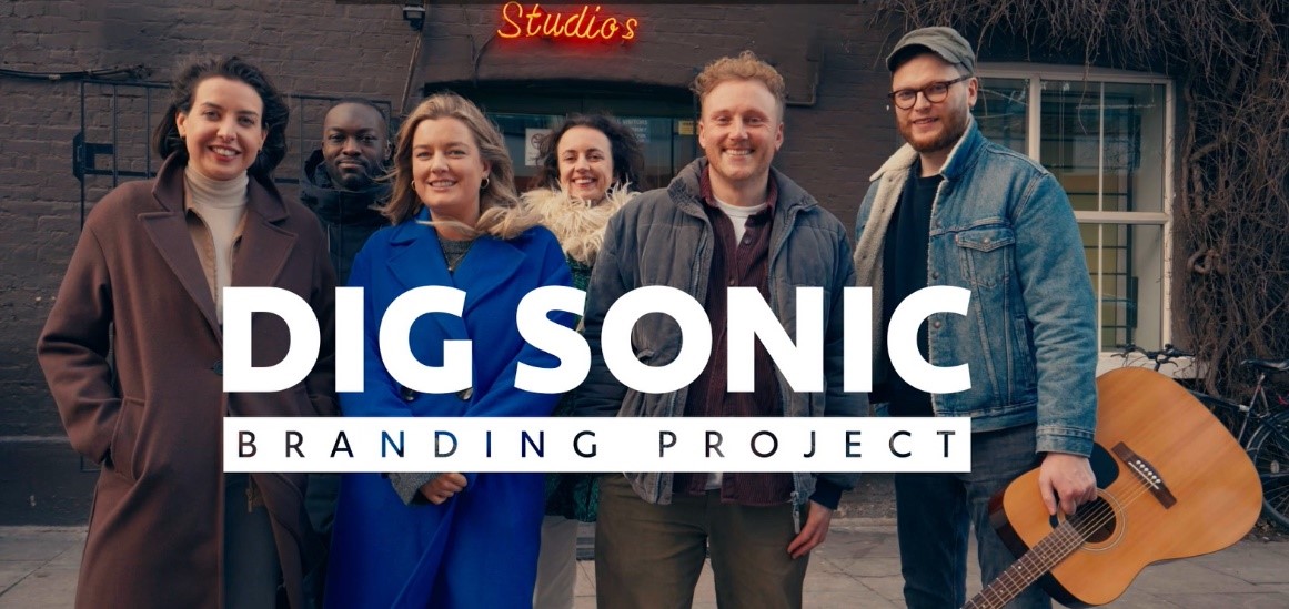 Image1 Six people stand in front of a studio, one with a guitar in hand, with the words 'DIG Sonic Branding Project'